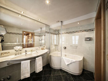 Großes Badezimmer mit Badewanne und schwarzen Bodenfliesen