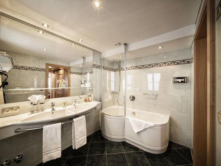 Großes Badezimmer mit Badewanne und schwarzen Bodenfliesen