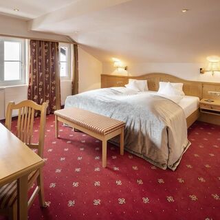 A double bed in the Junior suite with a red carpet and wood panelling