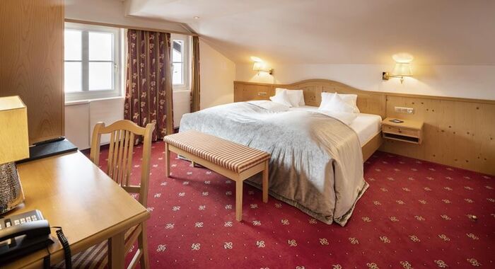 A double bed in the Junior suite with a red carpet and wood panelling