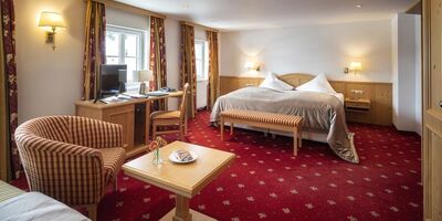 Doppelzimmer Deluxe mit rotem Teppich und Sitzgelegenheit