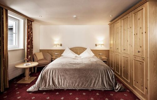 Double room with red carpet, a light wood wardrobe and a silver bedspread