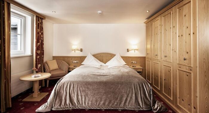 Double room with red carpet, a light wood wardrobe and a silver bedspread