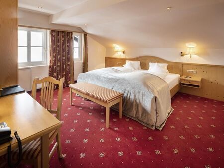 A double bed in the Junior suite with a red carpet and wood panelling