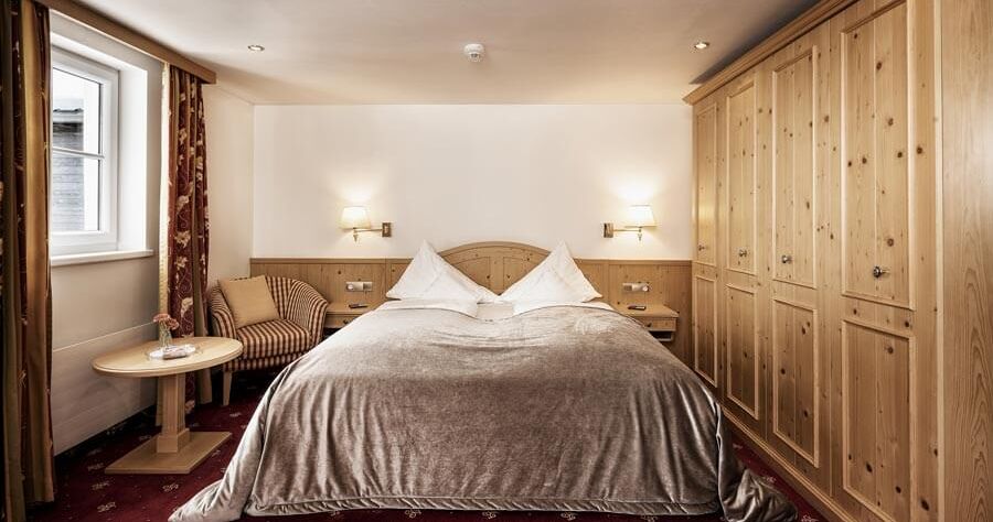 Double room with red carpet, a light wood wardrobe and a silver bedspread