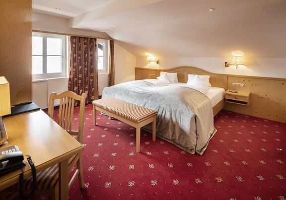 A double bed in the Junior suite with a red carpet and wood panelling