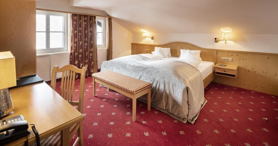 A double bed in the Junior suite with a red carpet and wood panelling