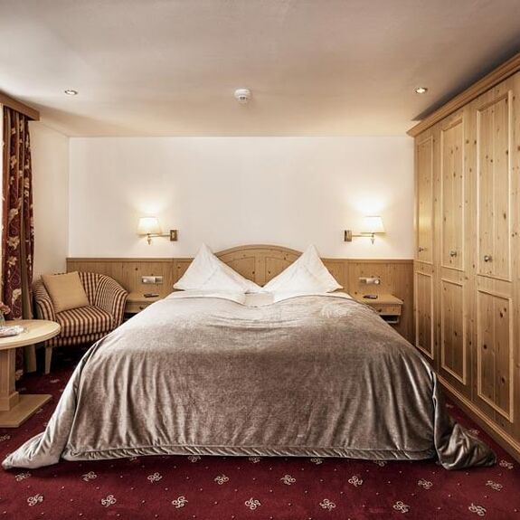 Double room with red carpet, a light wood wardrobe and a silver bedspread