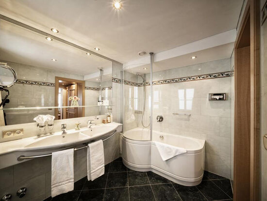 Großes Badezimmer mit Badewanne und schwarzen Bodenfliesen