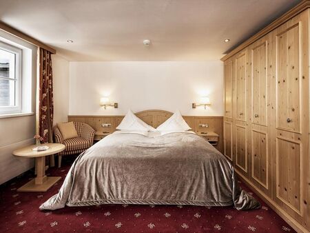 Double room with red carpet, a light wood wardrobe and a silver bedspread