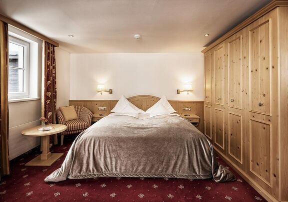 Double room with red carpet, a light wood wardrobe and a silver bedspread