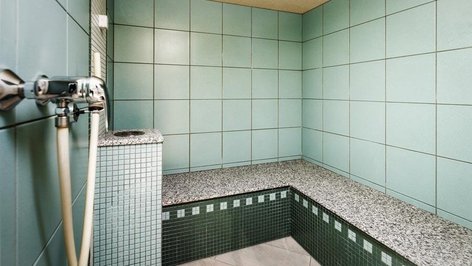 Spacious bathroom with turquoise tiles and a granite bench in the shower area, showcasing modern design.