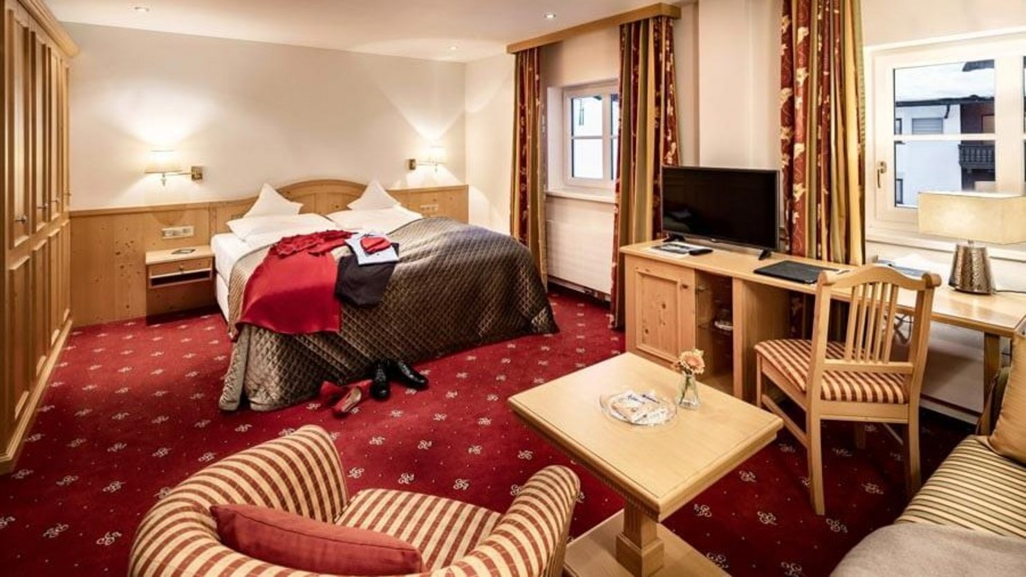 A well-furnished hotel room featuring a double bed, seating area, and desk for comfort and convenience.