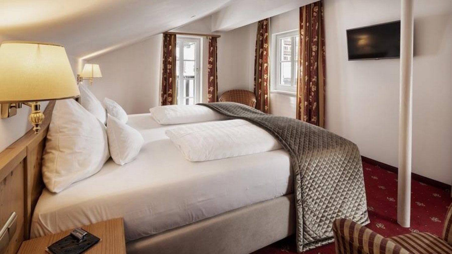 Modern hotel room with double bed and decorative pillows, designed for comfort and relaxation.