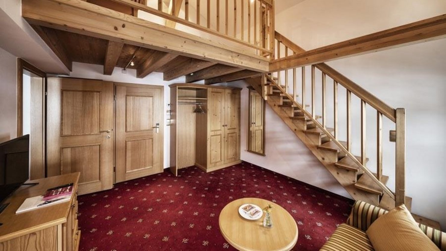 Hotel room featuring wooden staircase leading to loft area and cozy seating arrangement