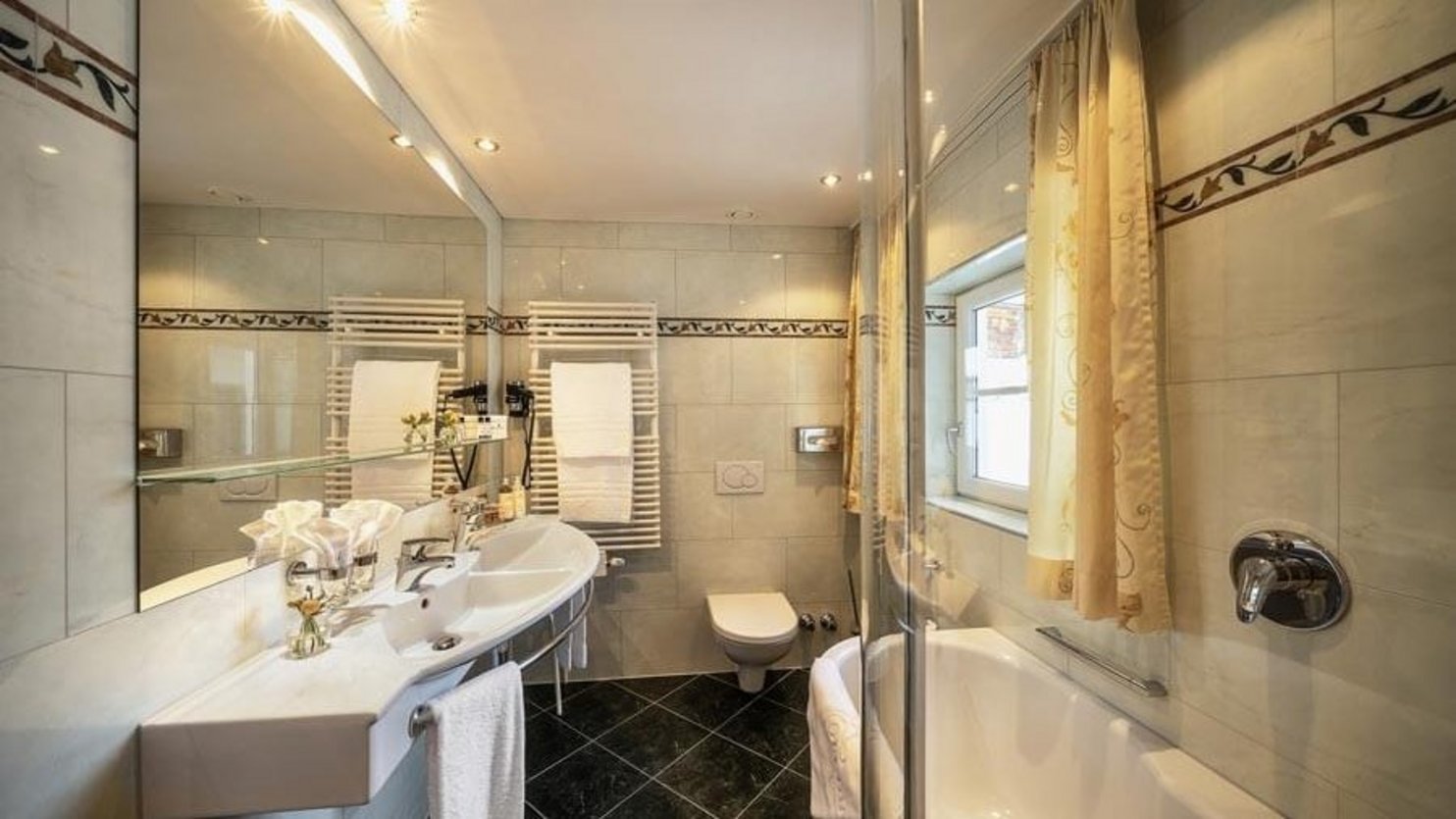 Contemporary bathroom with a bathtub, sink, and toilet featuring stylish tile work and ambient lighting
