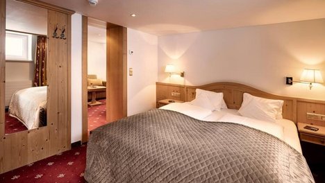 Behagliches Schlafzimmer mit Doppelbett und Holz Möbeln in einer Hotel Suite in Lech.