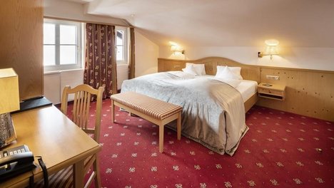 Hotelzimmer mit Doppelbett, Schreibtisch und Sitzbereich in einem eleganten Design