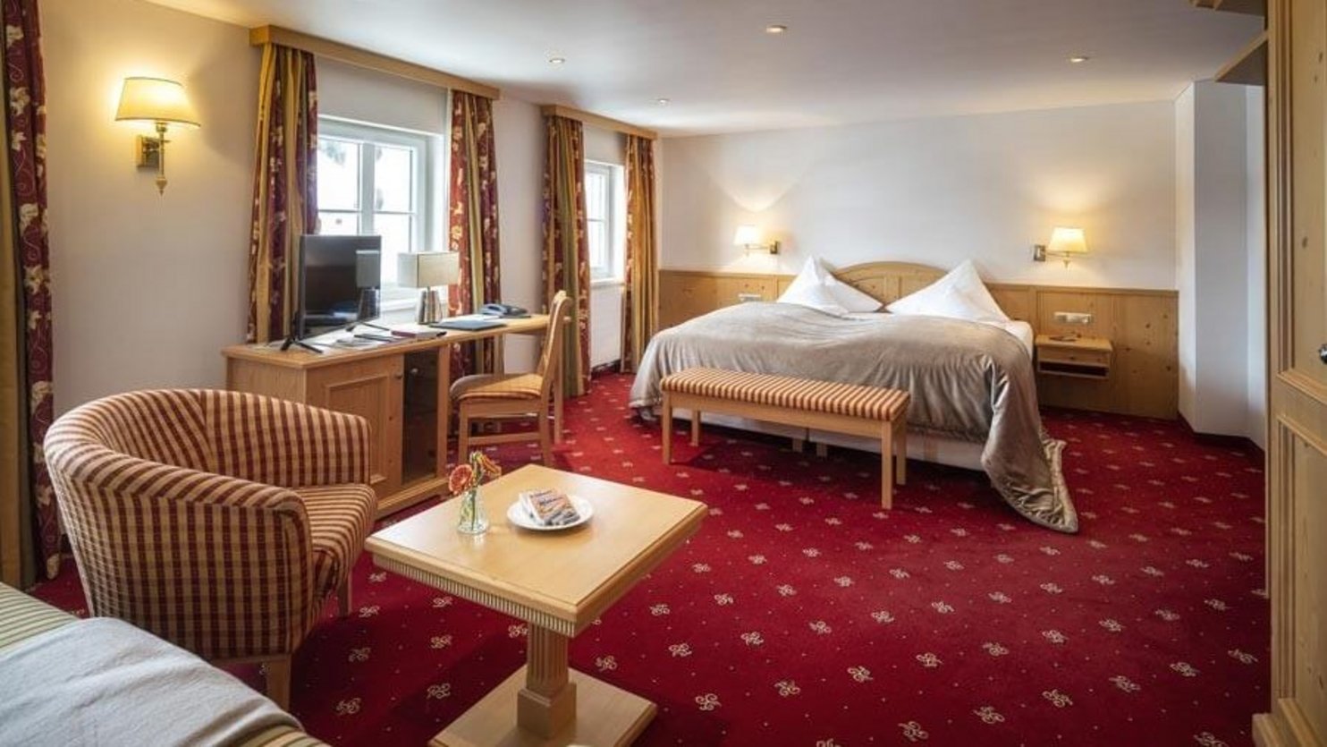 Elegant hotel room with luxury furnishings A spacious hotel room featuring a large bed, seating area, and desk with a computer
