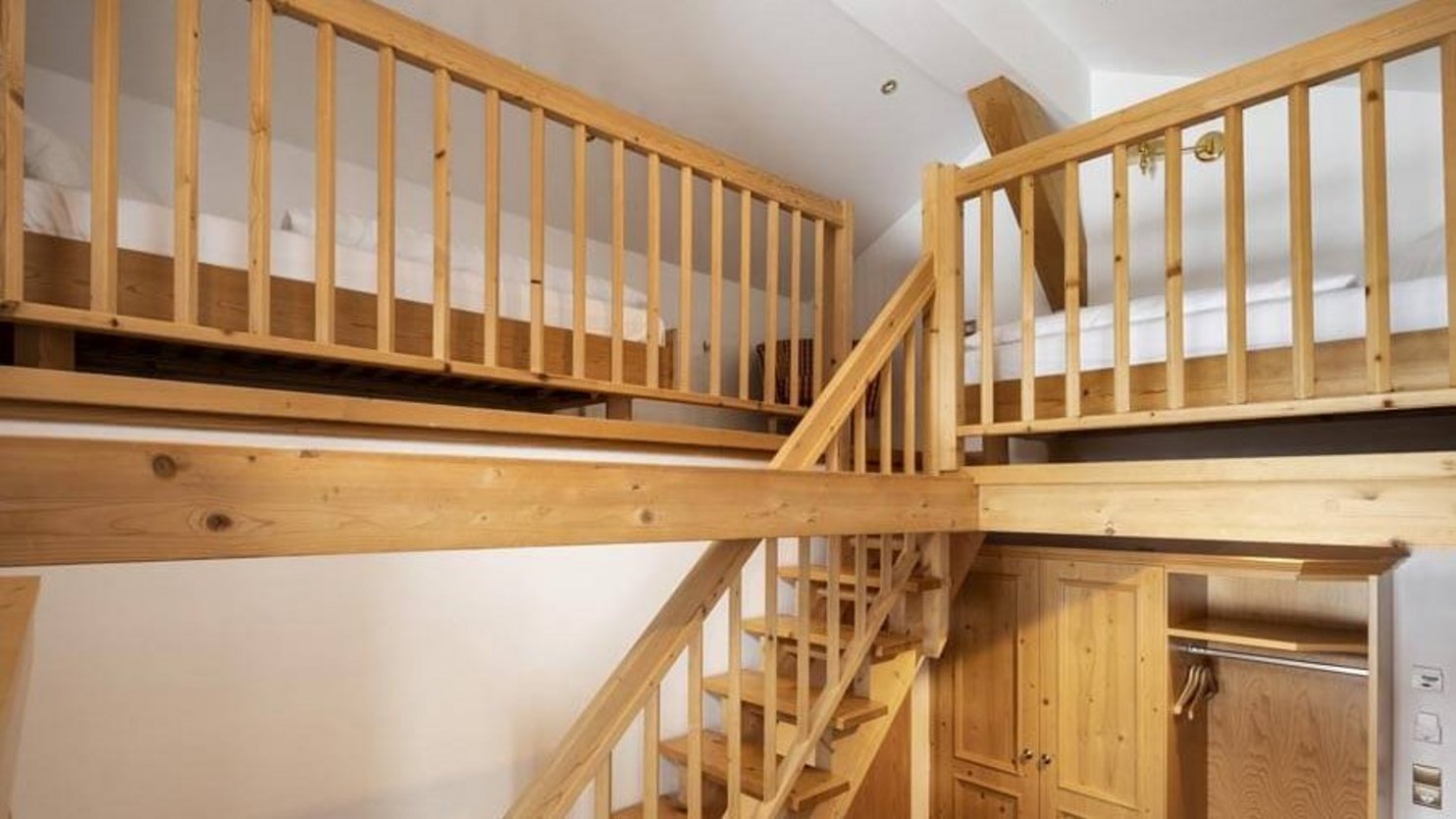 Loft-style bedroom featuring a wooden staircase and elevated sleeping areas separated by a railing