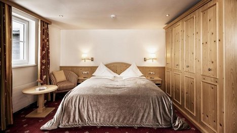 Furniertes Hotelzimmer mit großem Bett und Holzinterieur im sanften Licht, ideal für Erholung.