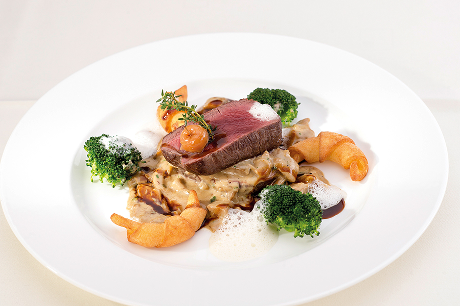 Fillet of beef on a mushroom ragout with broccoli and puff pastry on a white plate in the restaurant at the Tannbergerhof in Lech © Foto Lehmann