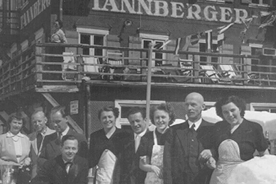 Ein altes schwarz-weiß Bild, worauf viele Menschen zu sehen sind und ein Ehepaar im Mittelpunkt steht, die Hoteleigentümer