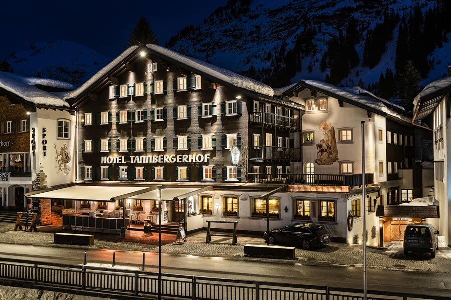 The Hotel Tannbergerhof in Lech shines at night, surrounded by snow-covered Vorarlberg mountains © Foto Lehmann