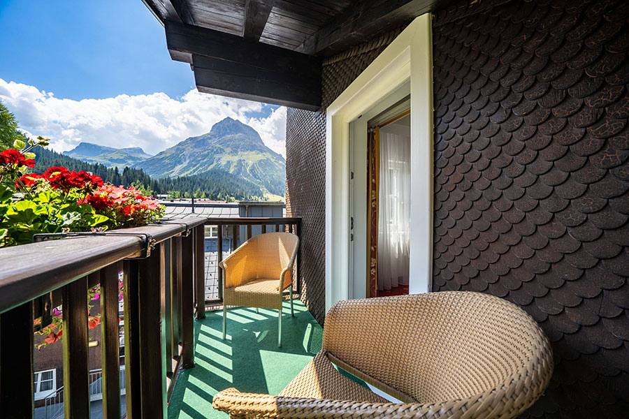 Balcony with cosy seating and flowers, with a view of the impressive mountain landscape of Lech am Arlberg © Foto Lehmann
