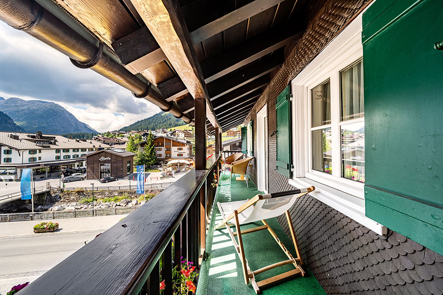 Balcony with wooden railings, two deckchairs and a view of Lech and the surrounding mountain landscape on the Arlberg © Foto Lehmann