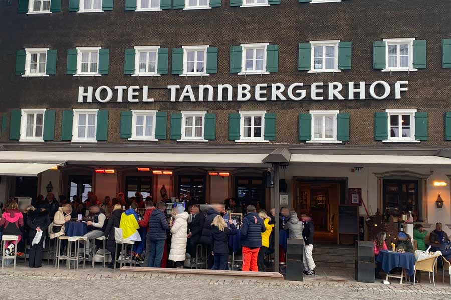 Belebte Terrasse des Hotel Tannbergerhof mit Gästen in winterlicher Kleidung, während Heizstrahler für eine gemütliche Atmosphäre sorgen