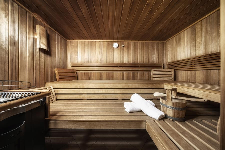Die Holzsauna mit Bänken, Aufgusseimer, Handtüchern und Saunasteinofen im Tannbergerhof in Lech © Foto Lehmann